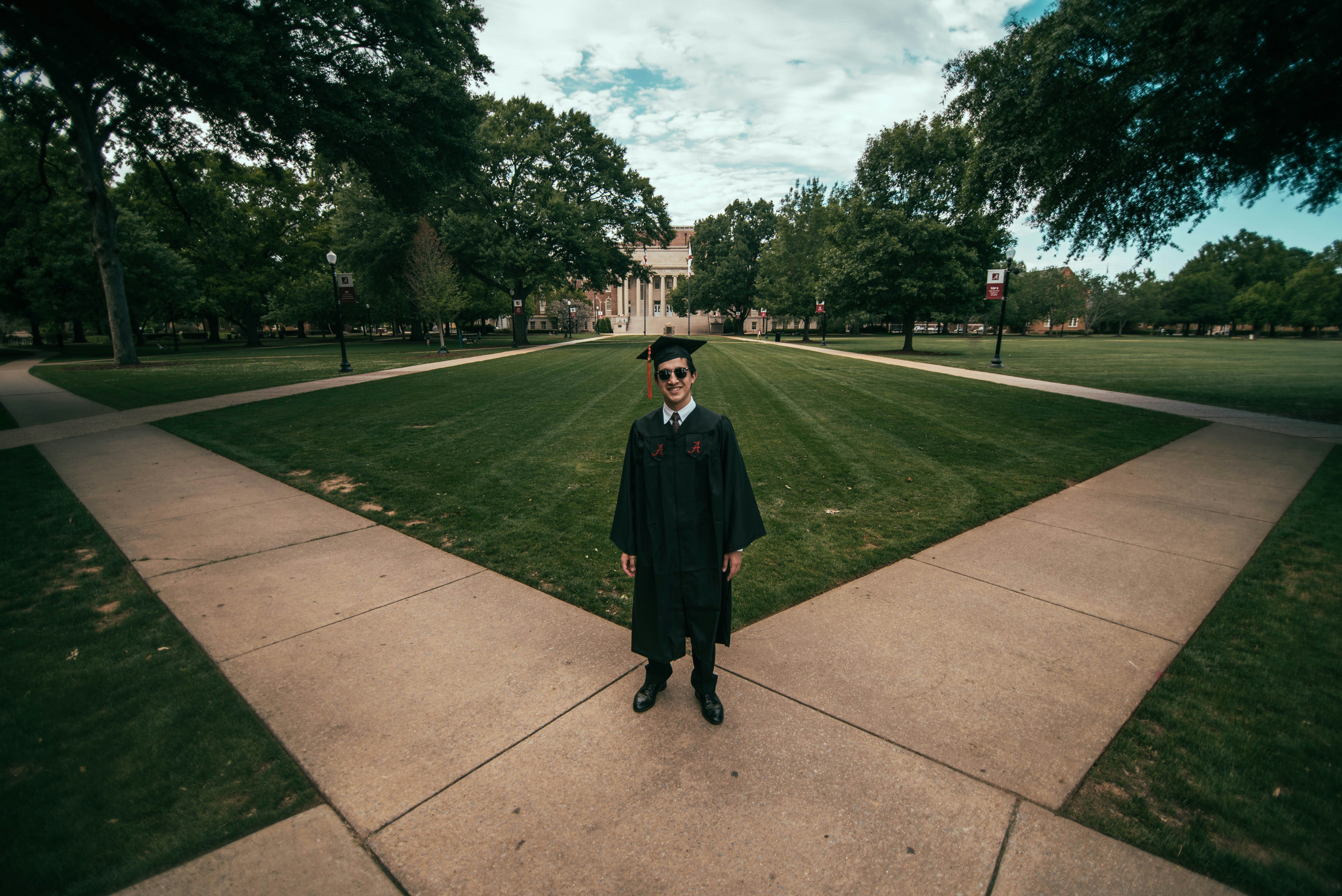 man wearing academic gown standing on green field